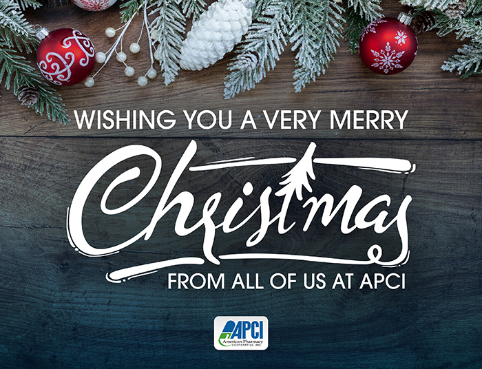 Image of pine cones, greenery, and Christmas ornaments on a background of dark wooden planks with a Christmas message from APCI